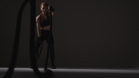 Studio-Shot-Of-Mature-Woman-Wearing-Gym-Fitness-Clothing-Doing-Cardio-Exercise-With-Battle-Ropes-1